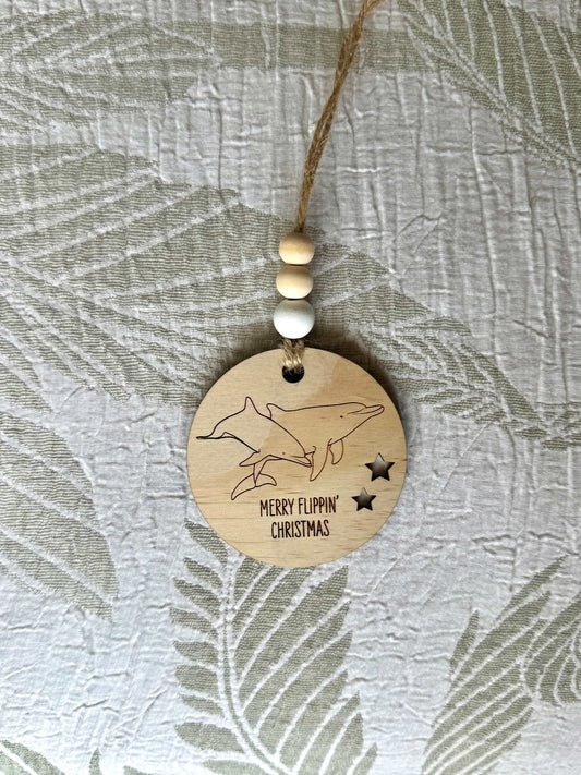 Wooden Christmas decoration with etched dolphins and "Merry Flippin' Christmas" text, natural beads and jute string hanging ornament