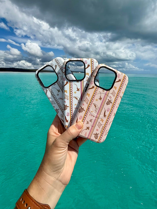Hand holding Candy Stripes Ocean Inspired phone cases with a scenic ocean Kgari Fraser Island and sky background
