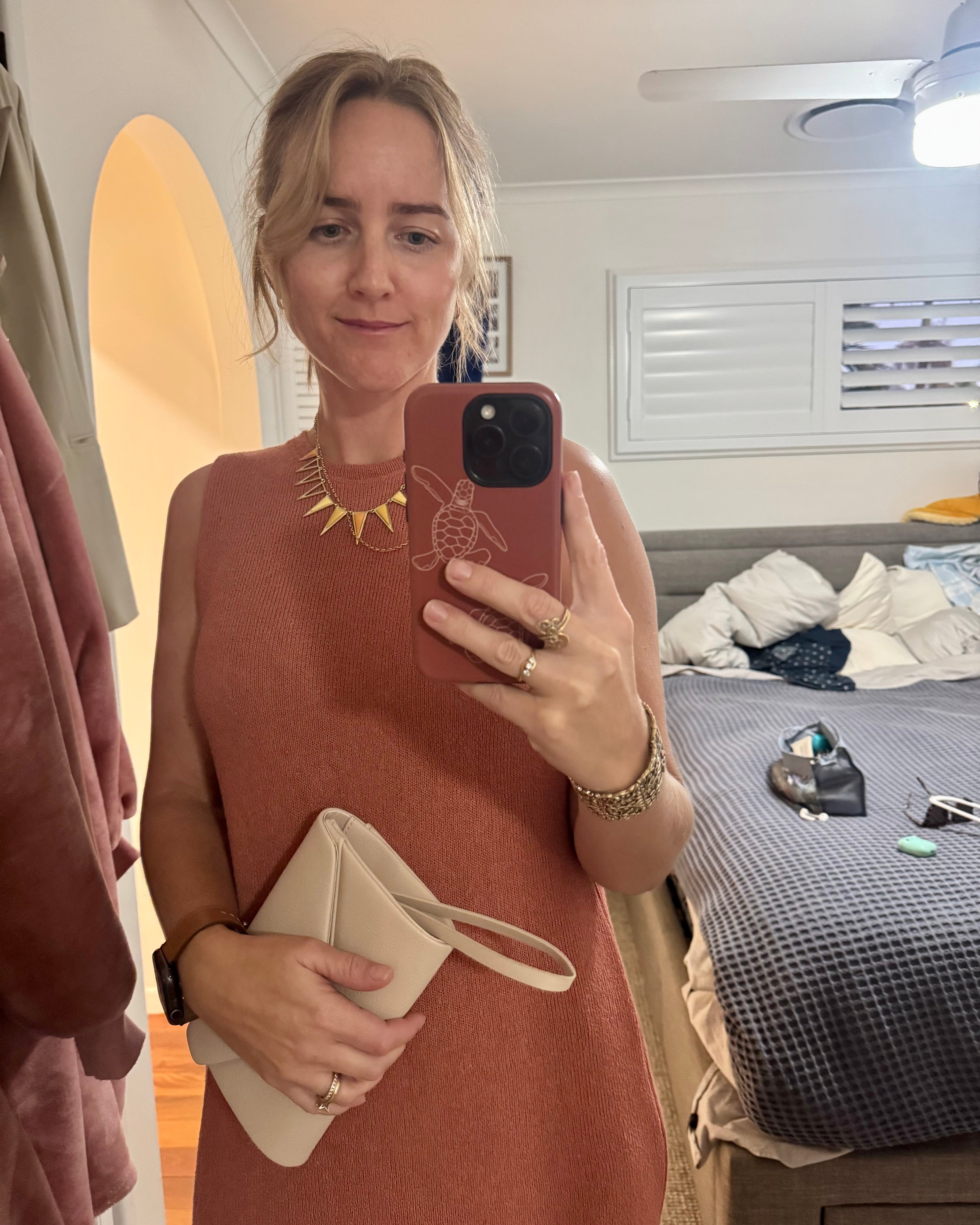 Steph taking a mirror selfie wearing a rust-colored dress with matching rust turtle hatchling phone case.
