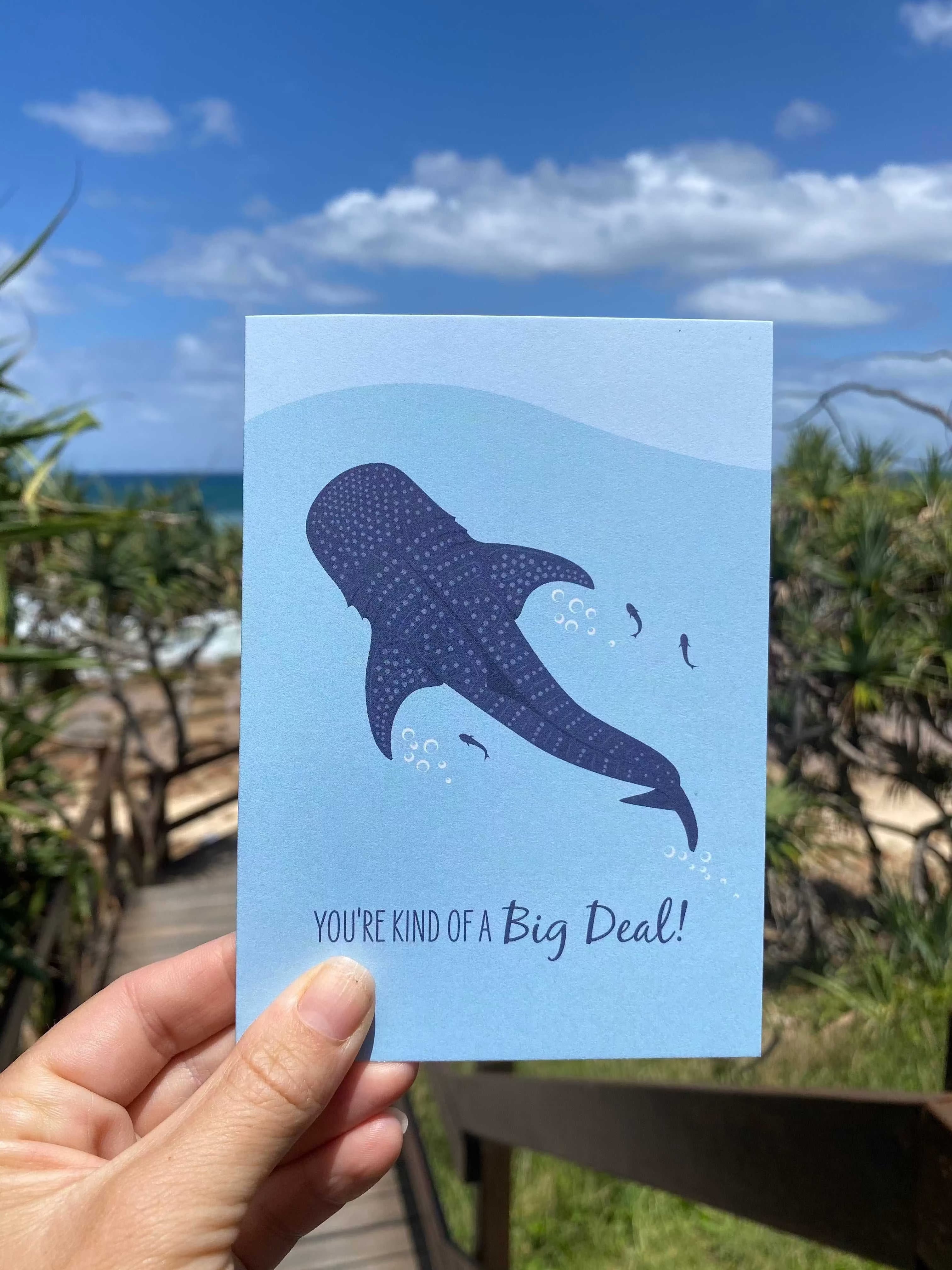 Whale shark greeting card with ocean design and "You're kind of a Big Deal!" text, held outdoors with sea background