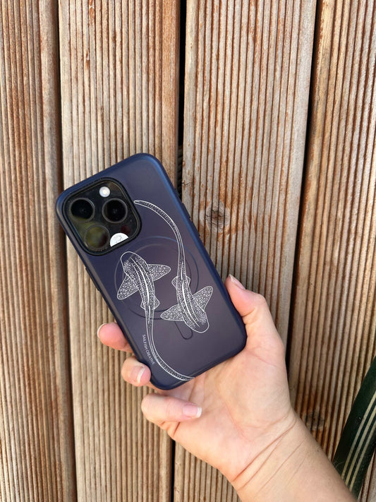Navy iPhone phone case with white leopard shark outline design held in hand against wooden background
