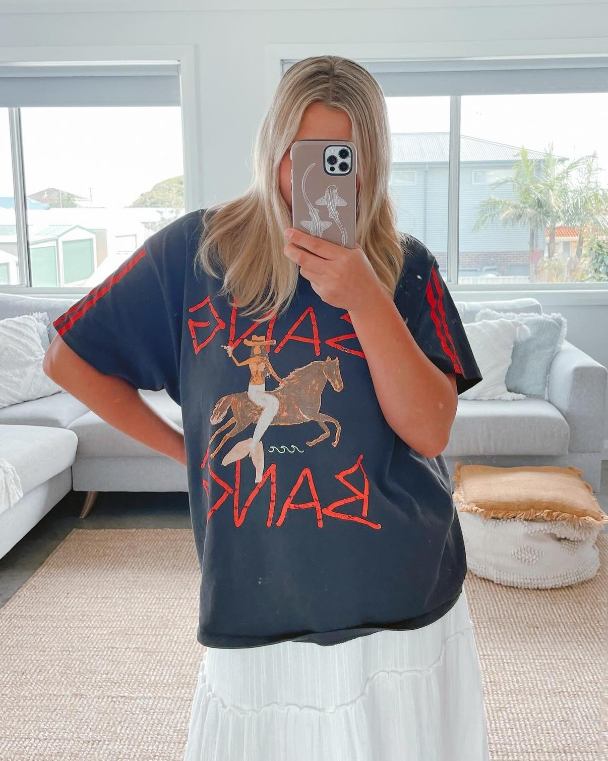 Person wearing a graphic mermaid tahnee kelland t-shirt  and leopard shark outline natural iphone phone case