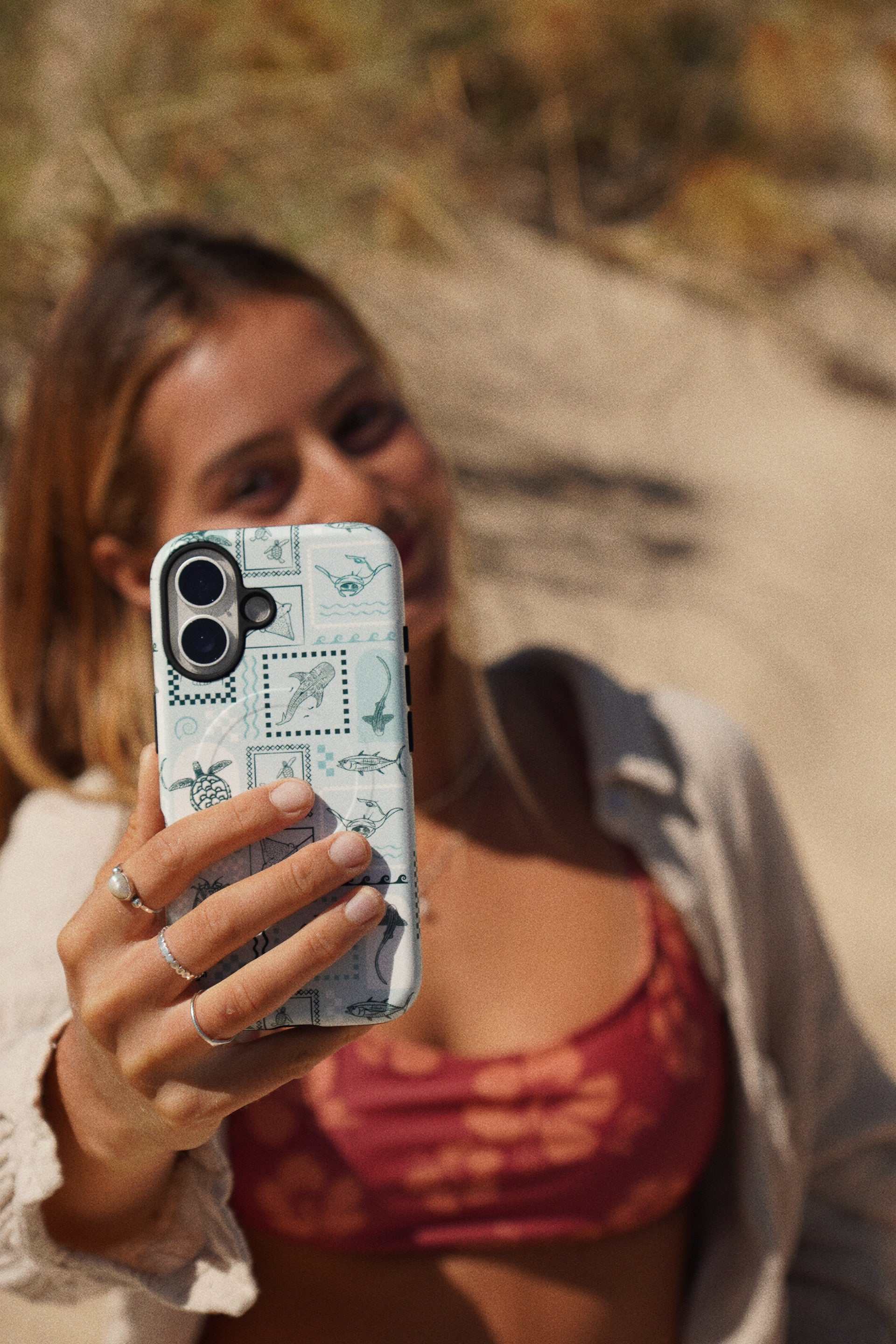 iPhone phone case with teal arches print held by person outdoors