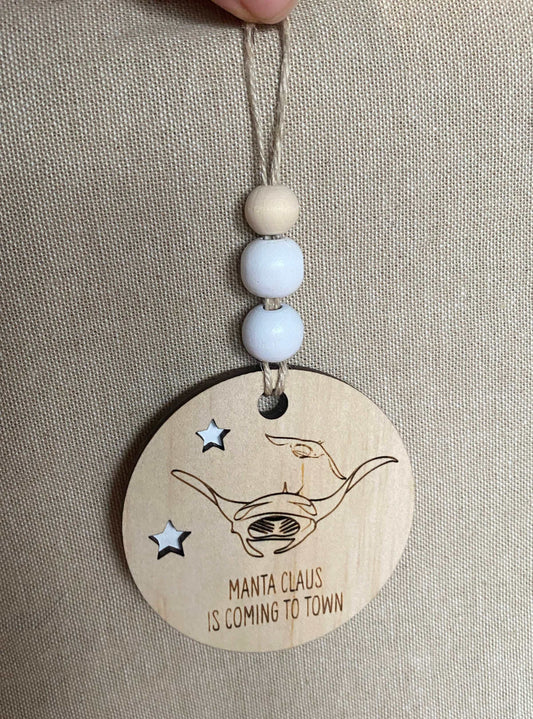 Wooden Christmas decoration featuring a manta ray with "Manta Claus is coming to town" text and hanging beads