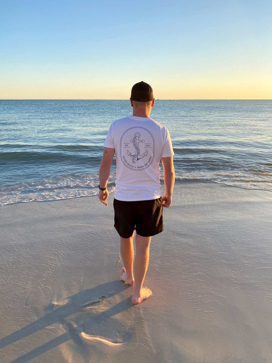 Man wearing Making Ship Happen mens nautical t-shirt with anchor design walking on beach by ocean
