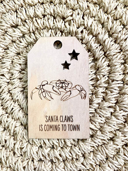 Wooden Christmas swing tag with crab illustration and "Santa Claws is Coming to Town" text