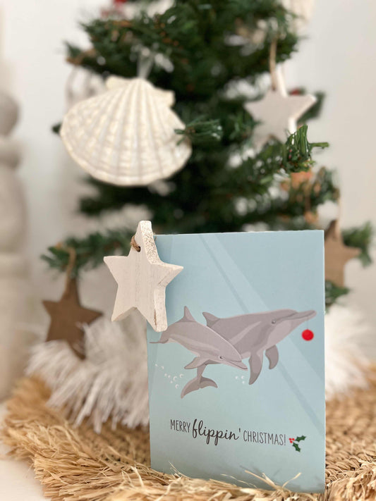 Christmas Card with dolphins illustration and "Merry flippin' Christmas" text, eco-friendly materials, and marine conservation donation.