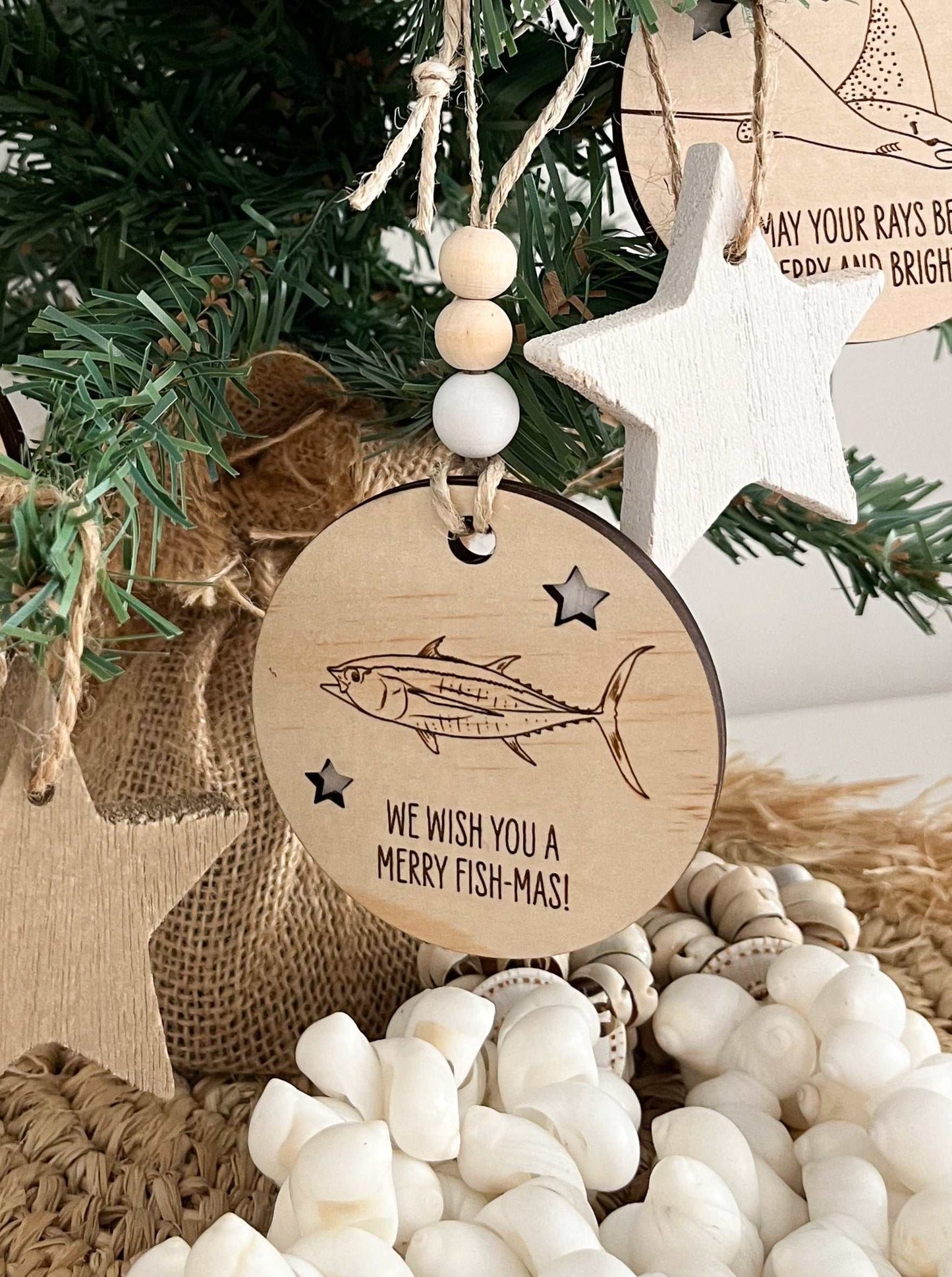 Wooden Christmas decoration featuring a tuna fish design and festive message hanging on a tree