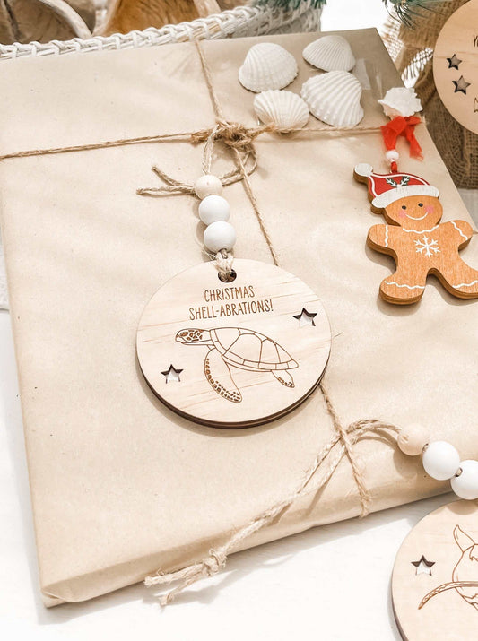 Wooden Christmas decoration featuring a green turtle engraving with "Christmas Shell-abrations" text on a wrapped gift