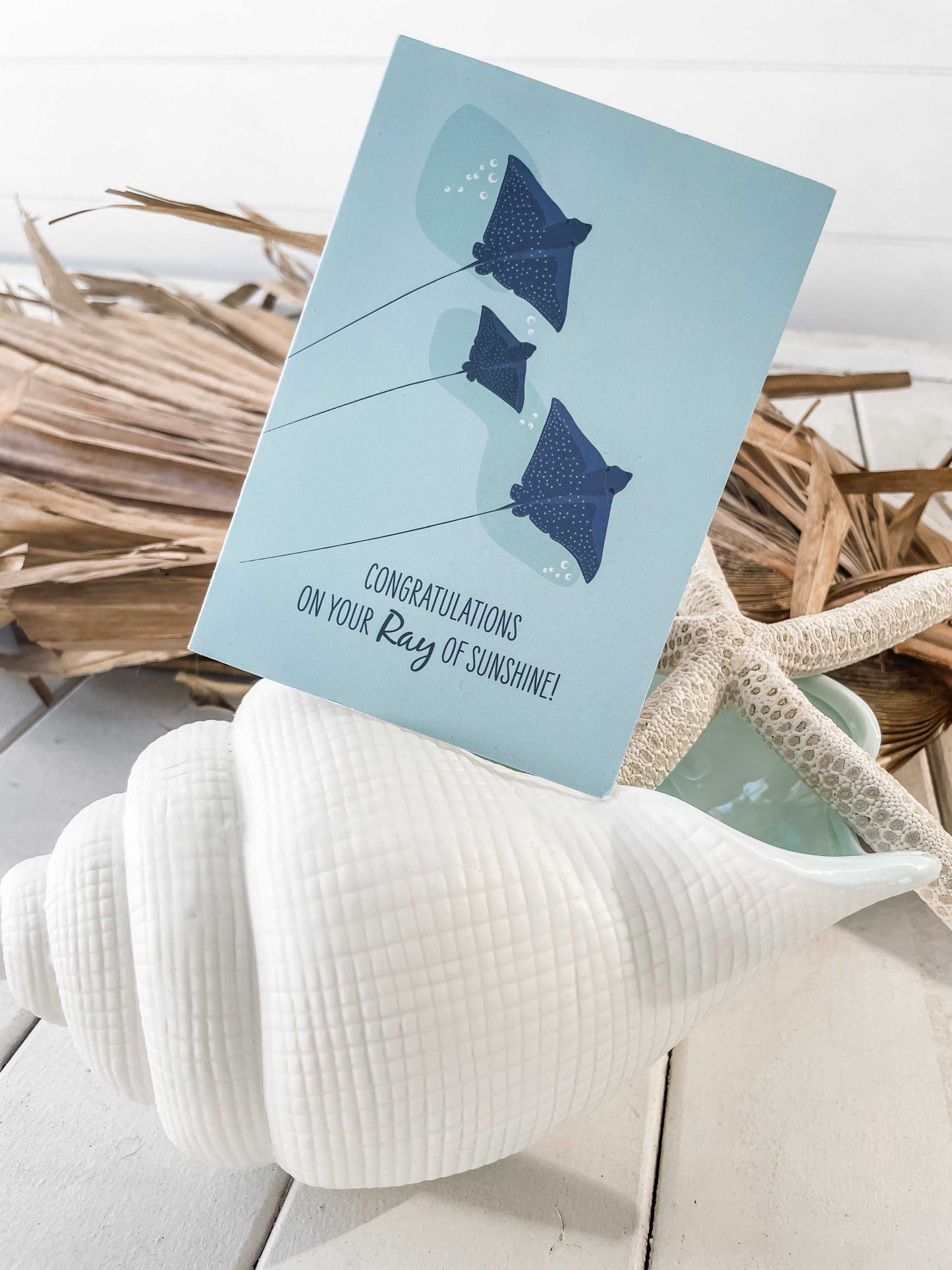 Baby card with spotted eagle rays illustration and congratulations message ocean theme