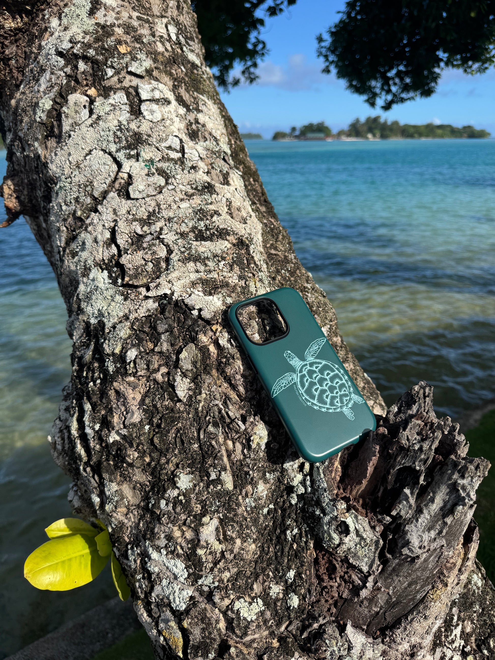 Phone case with turtle design on a tree branch by a water body